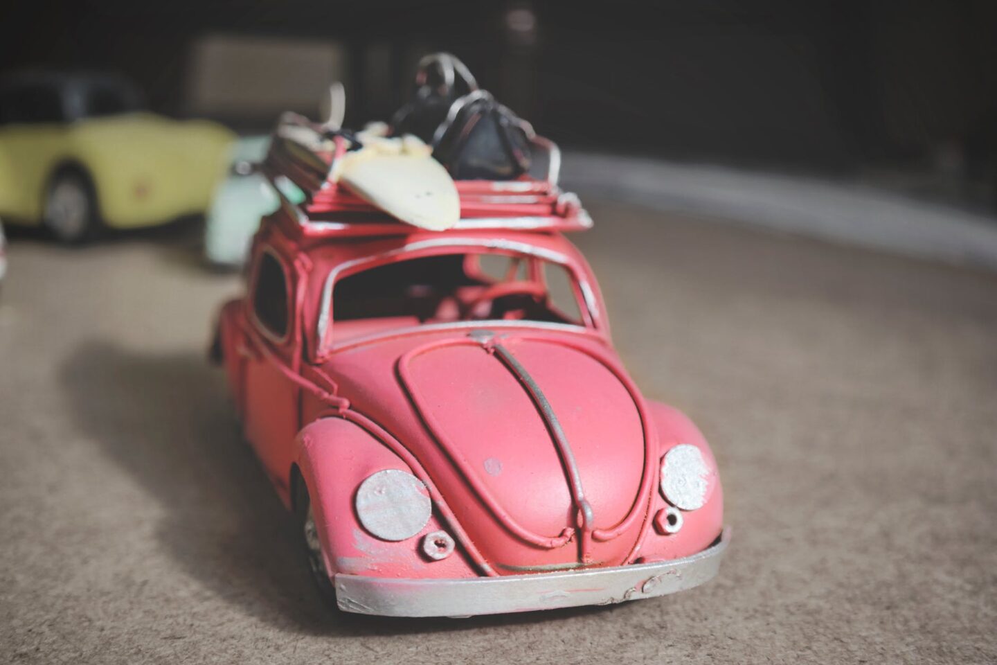 pink volkswagen beetle scale model on brown surface