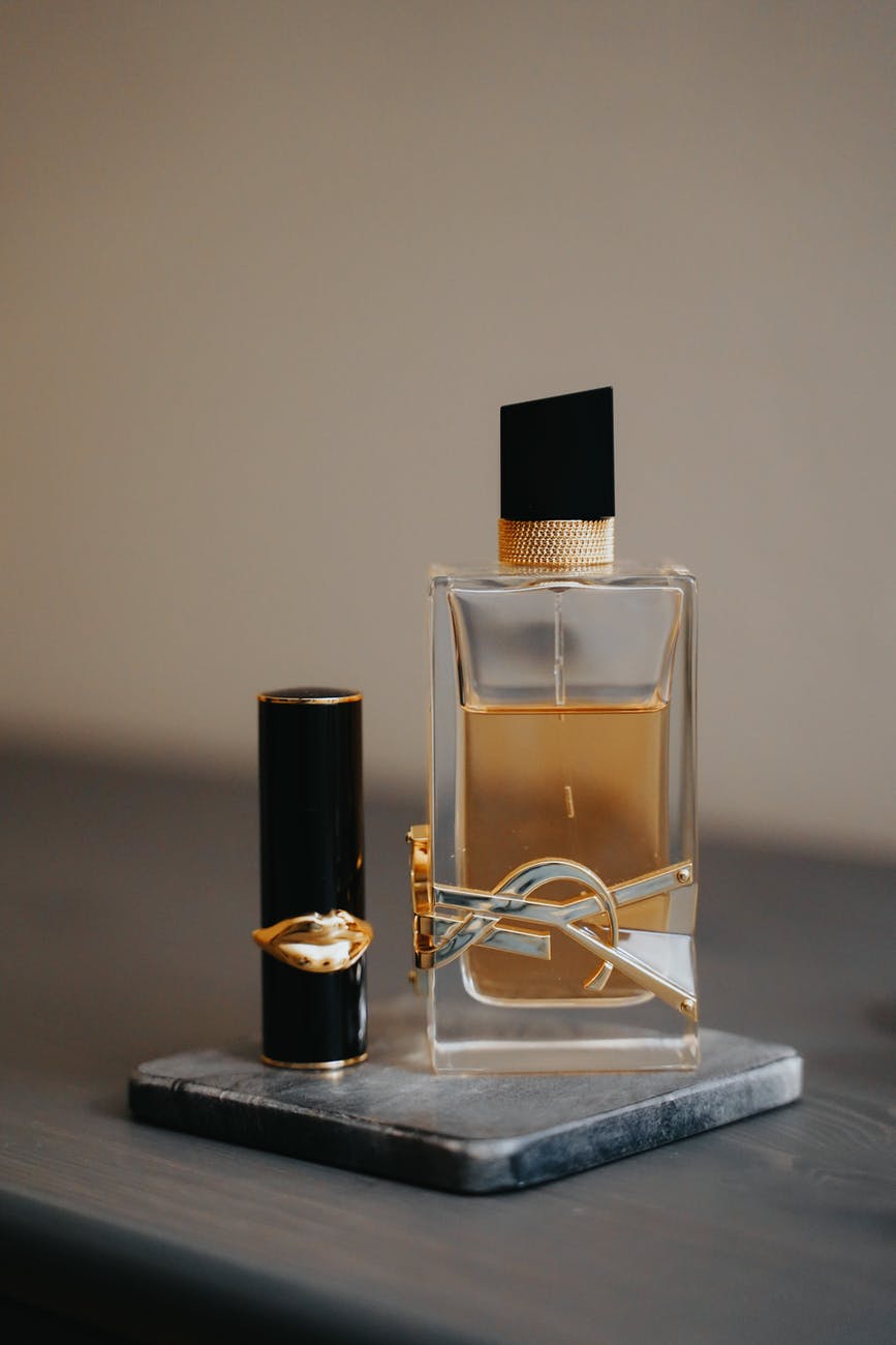 glass perfume bottle beside a lipstick
