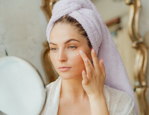 woman with head towel applying face cream